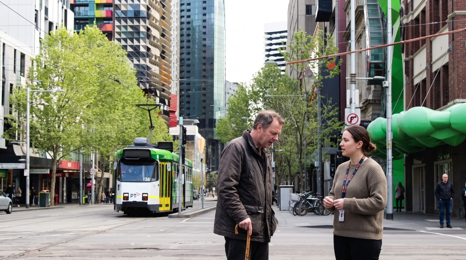 A man with a walking stick and his support worker talk at a Swanston Street tram stop as a tram arrives.