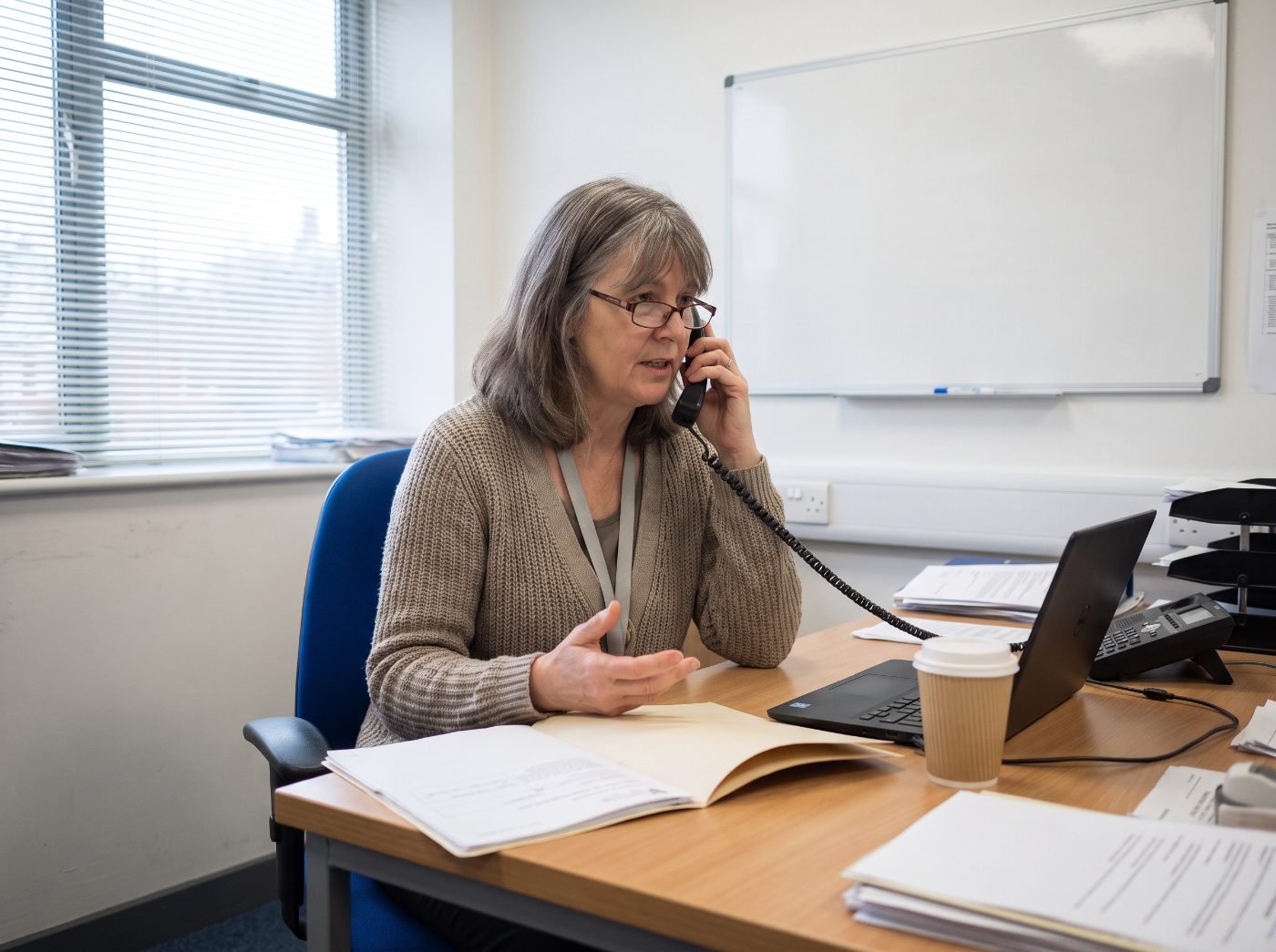A hospital social worker on the phone at her desk, making a referral.