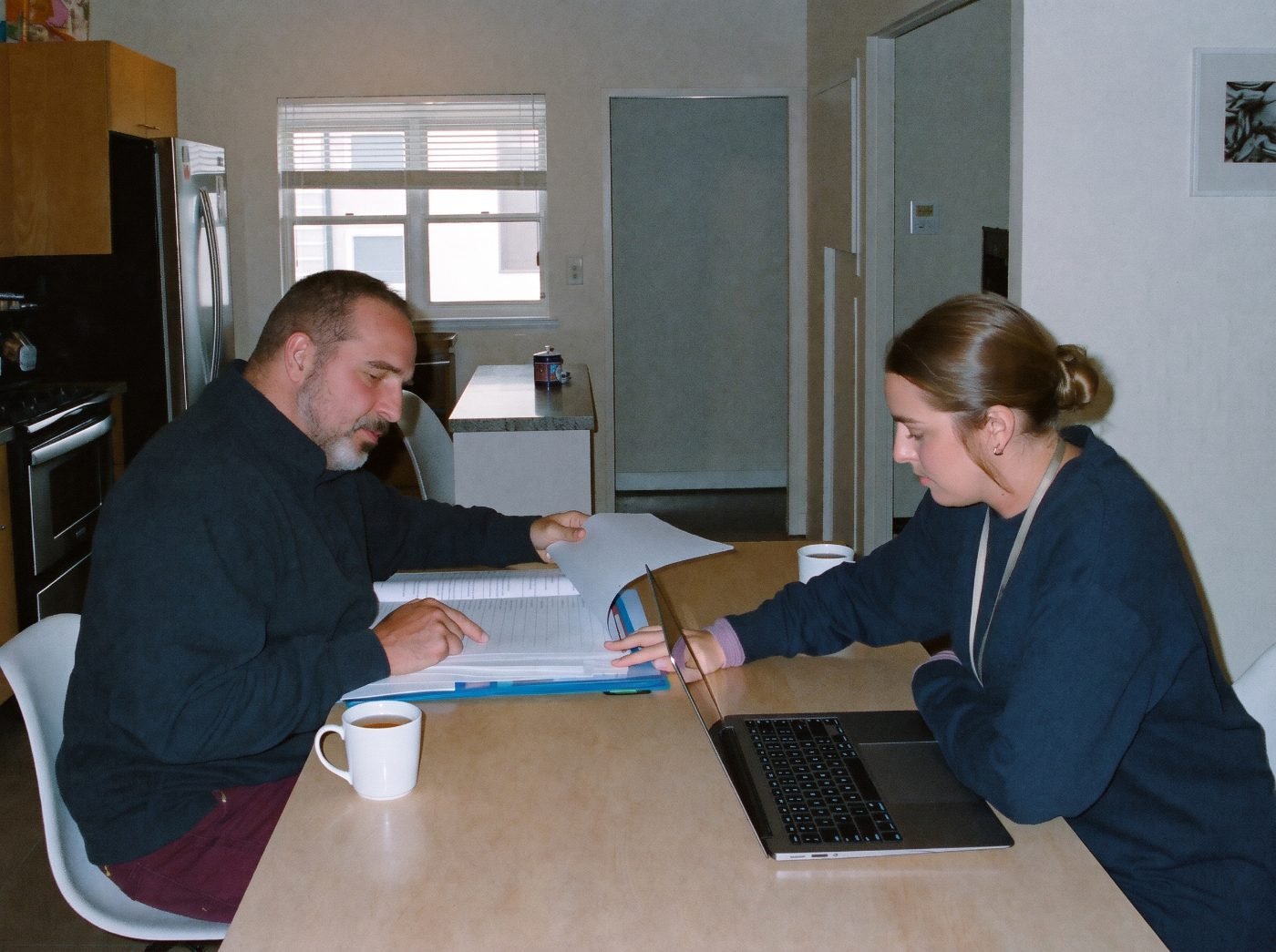 A man and his support coordinator go through his NDIS plan together at a kitchen table.
